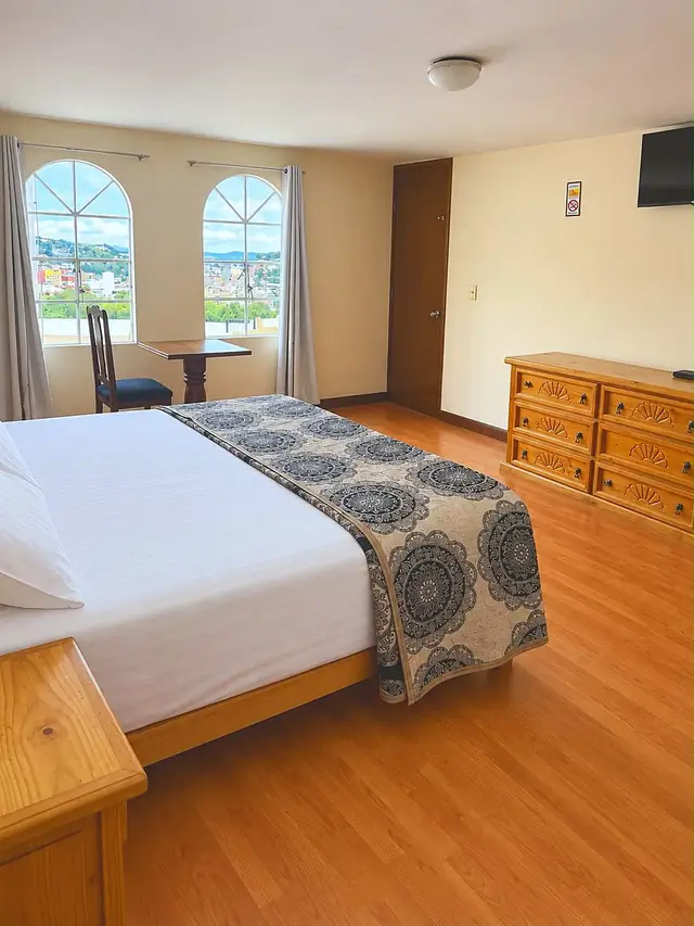 Habitación con dos ventanas de arco y vista a la ciudad