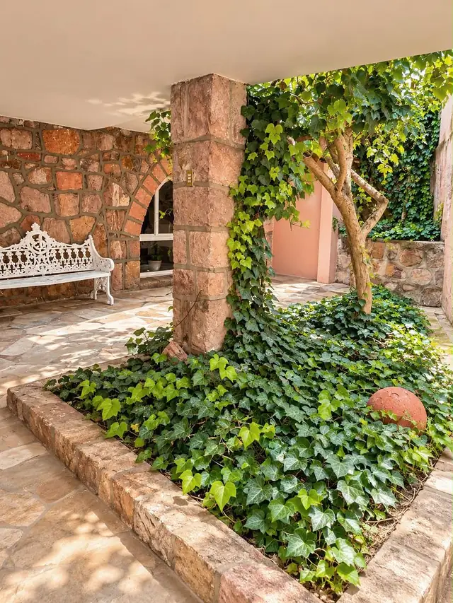 Jardín con hiedra y banca de herrería blanca