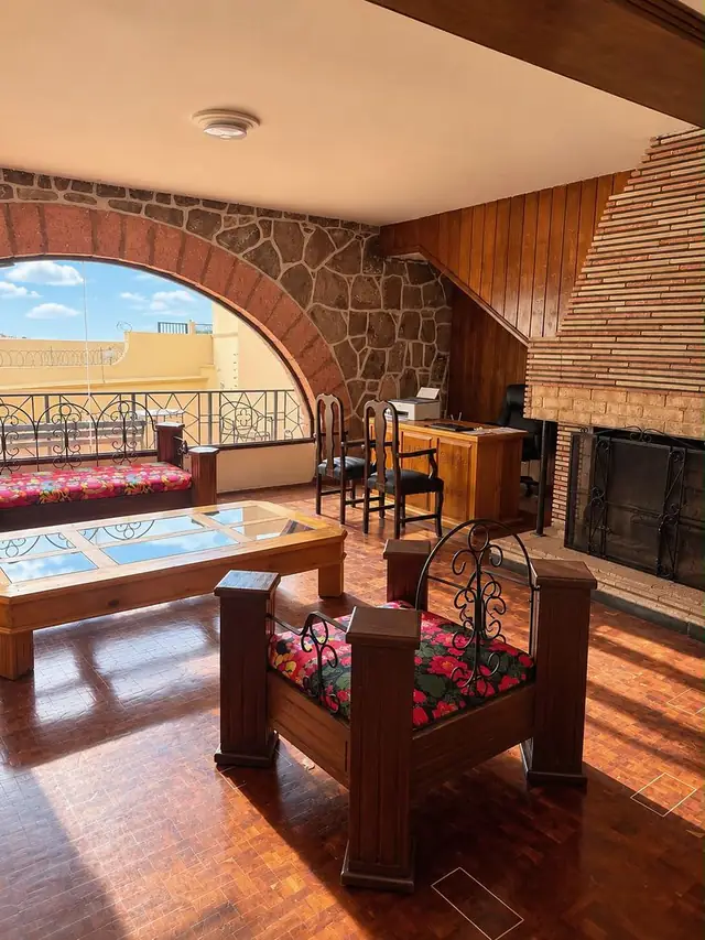 Sala de huéspedes con chimenea y arco abierto a la terraza